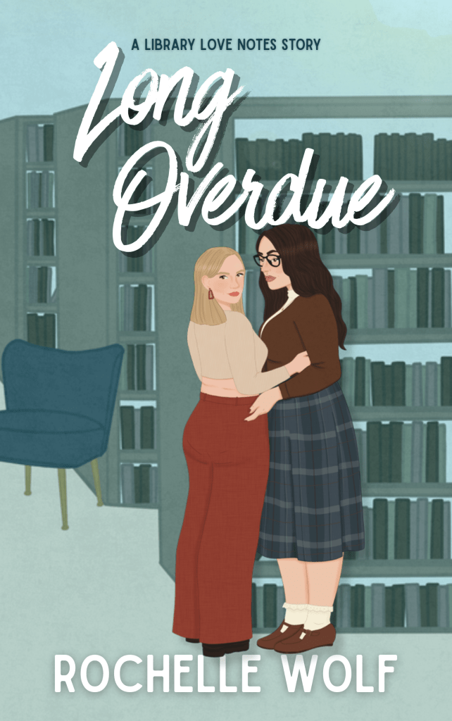 Two women are embracing in a library. A taller brunette white women looks fondly at the other woman, who is blonde.